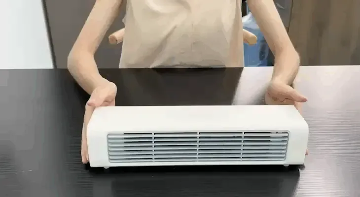 Hands placing the compact Qinux BreezaMax personal cooler on a desk, showing how small and portable the cordless unit is